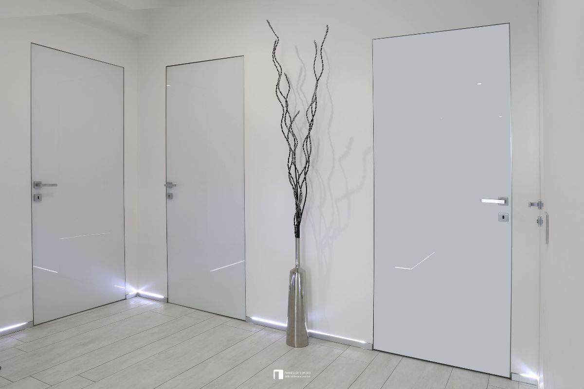 Porte battenti filomuro con maniglia quadra e finitura in vetro bianco